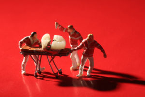 Miniature model of 3 paramedics pulling a cracked tooth on a gurney